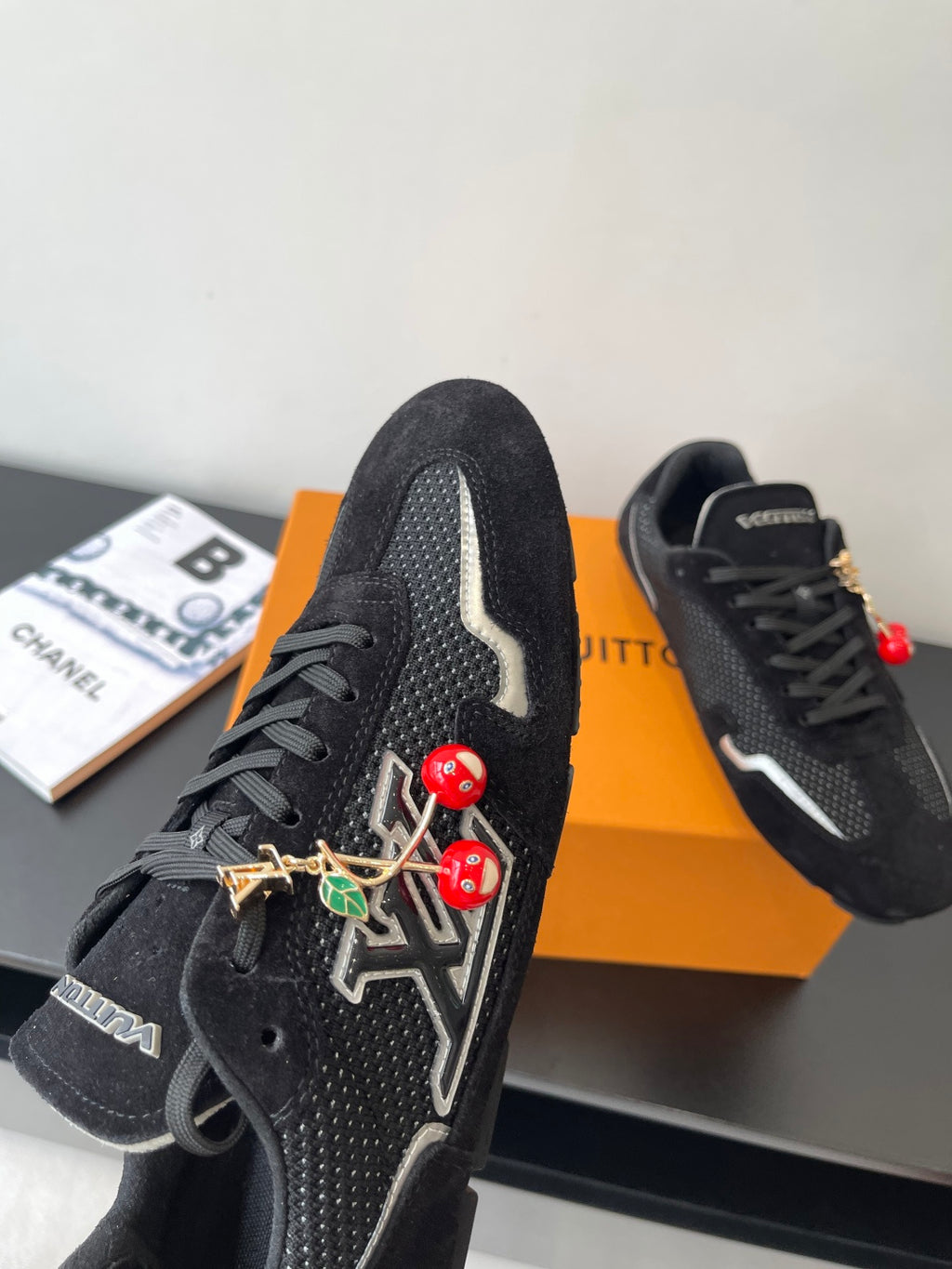 Black Louis Vuitton sneakers, side view with white logo stripe and charms
