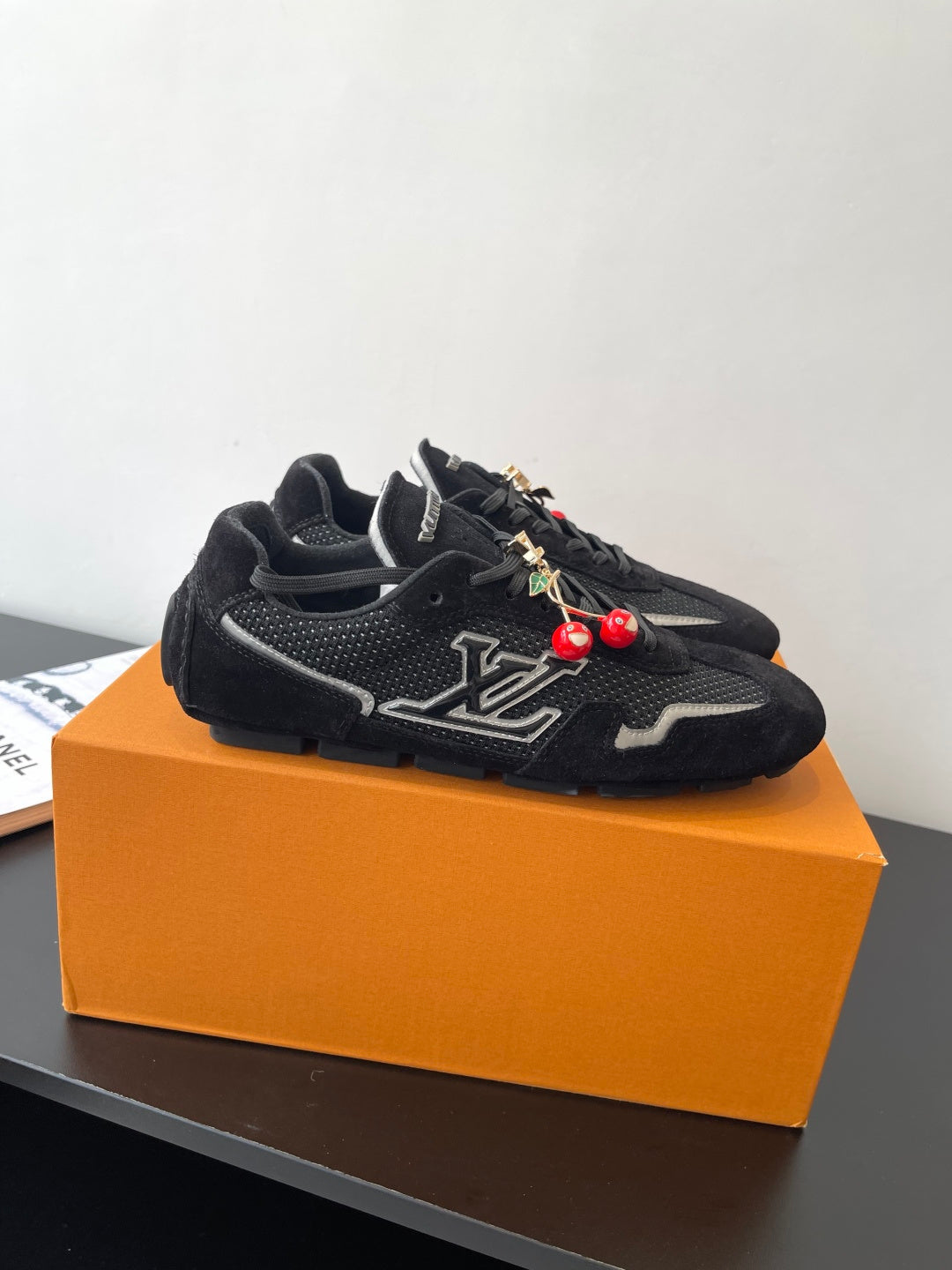 Black Louis Vuitton sneakers, side view with LV emblem and charm accents