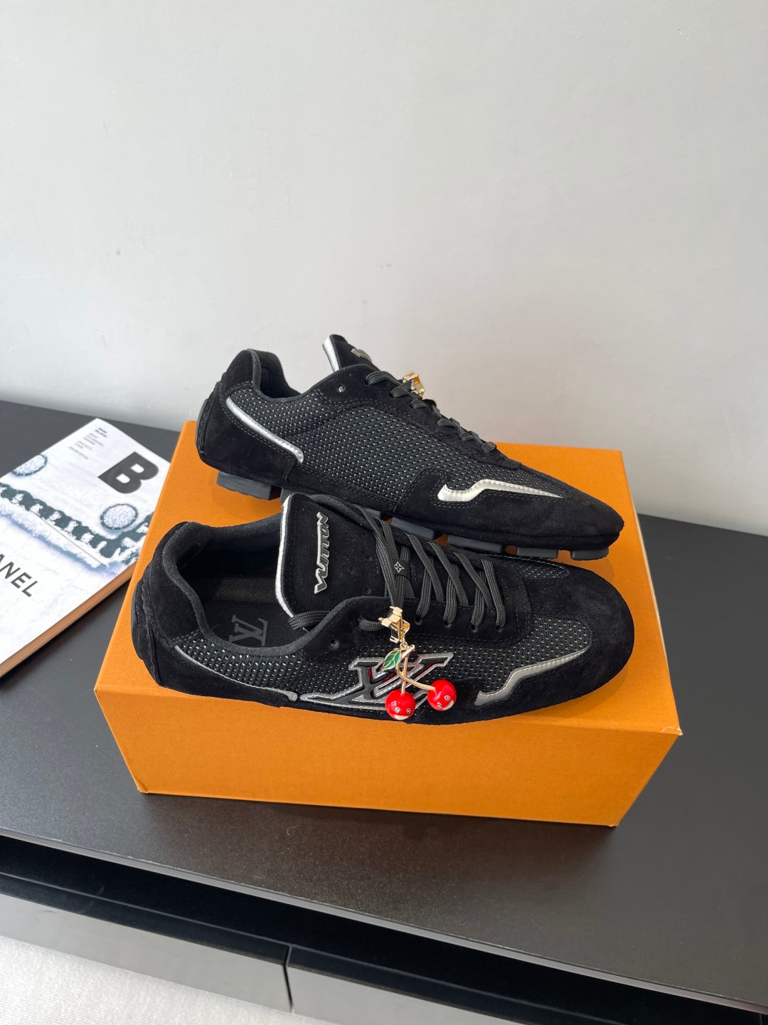 Black Louis Vuitton sneakers, angled side view with LV logo and red charms
