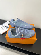 Light-blue lace-up sneakers side view with textured overlays and red charm accents
