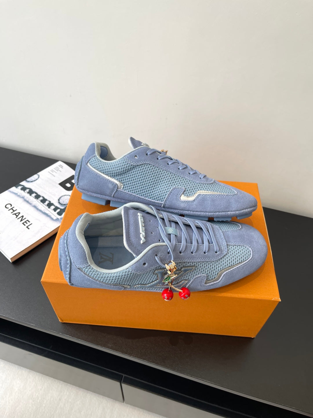 Light-blue lace-up sneakers side view with textured overlays and red charm accents