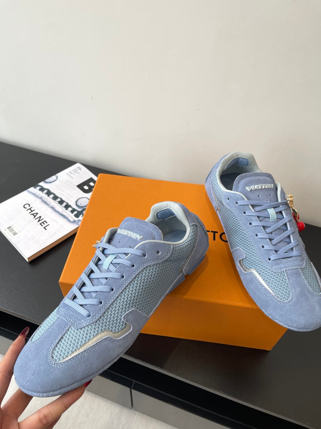 Light-blue lace-up sneakers with raised side logo detail and red-and-gold charm accents