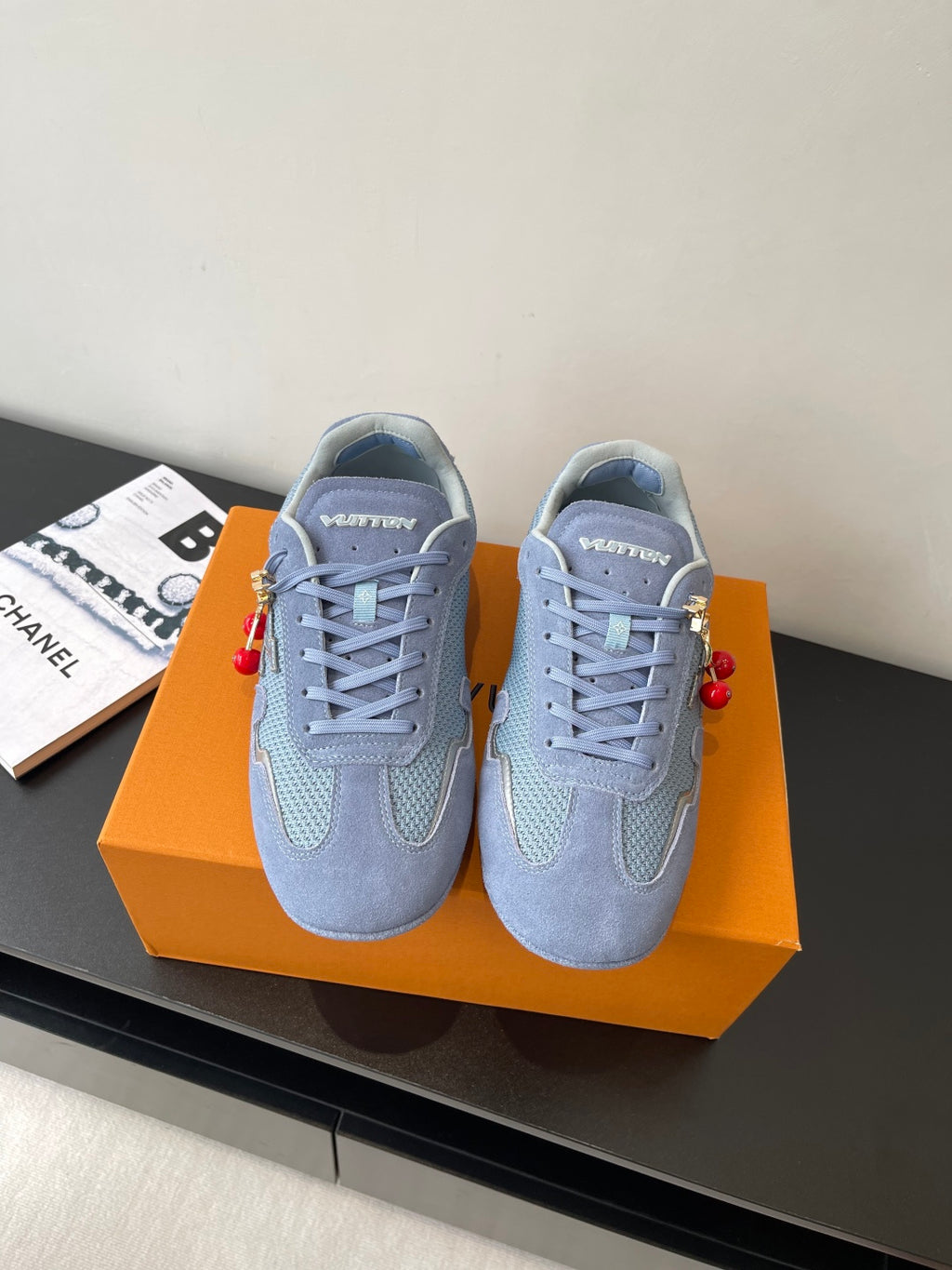 Light-blue lace-up sneakers with padded collar, tonal panels, and red charm accents