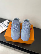 Light-blue lace-up sneakers with padded collar, tonal panels, and red charm accents