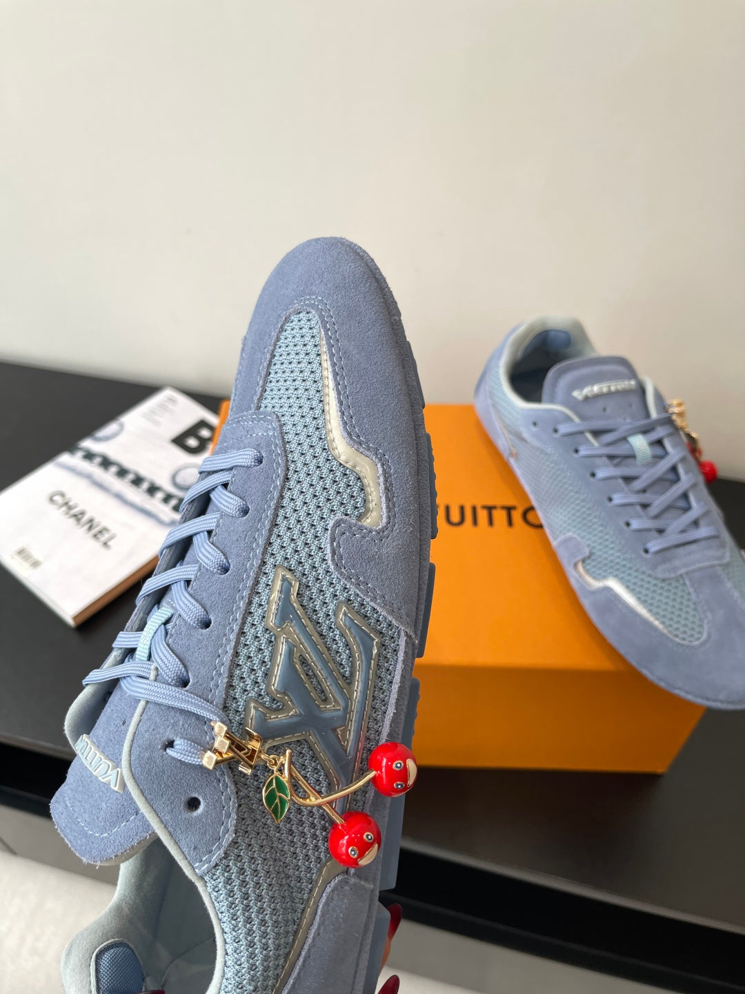 Light-blue lace-up sneakers with gold-and-green embroidered side detail and red charms