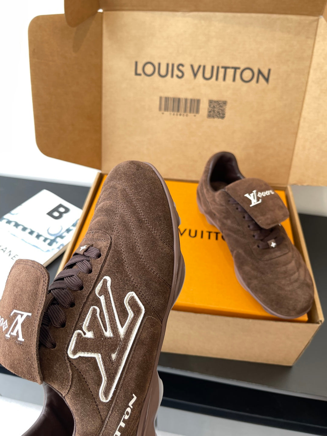 Brown suede lace-up sneakers with white LV graphic on side