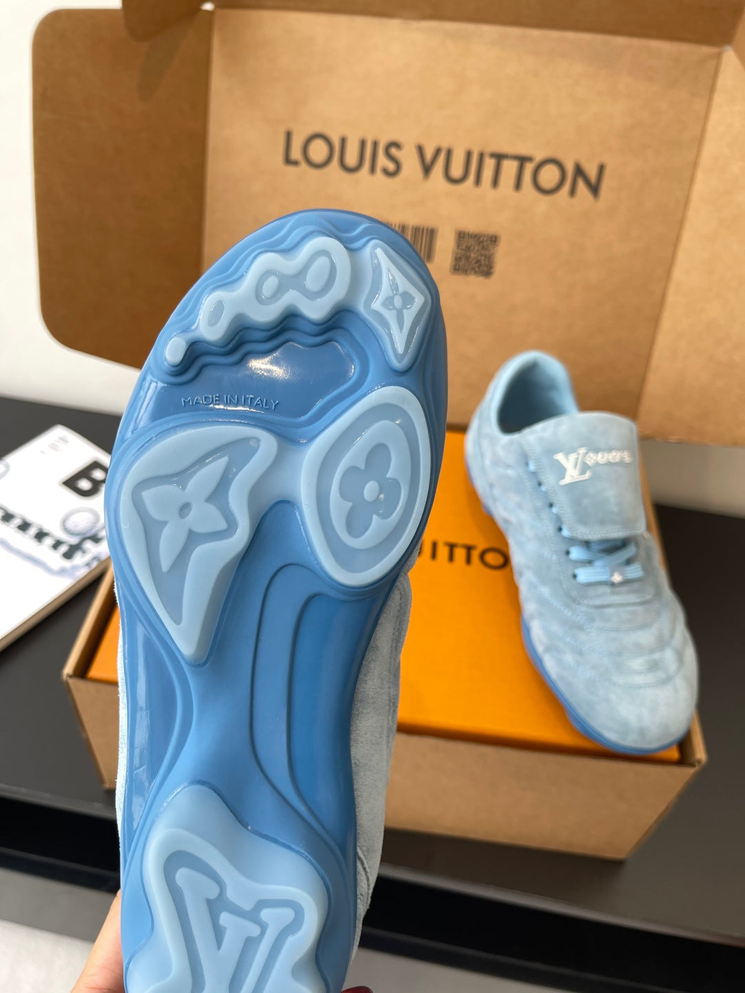 Light blue sneaker outsole with embossed tread, pair shown in open box
