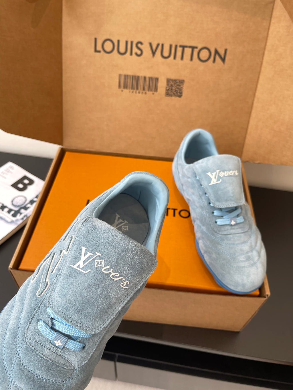 Light blue suede sneakers with Louis Vuitton logo, front close-up in open box