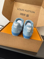 Light blue sneakers with rear logo patches, pair shown in open gift box