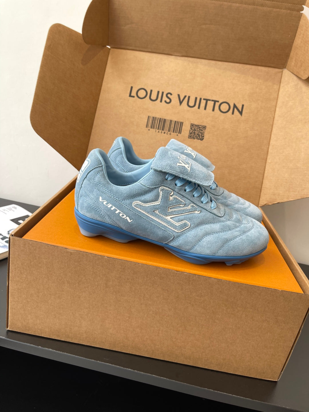 Light blue lace-up sneaker with Louis Vuitton logo, side view in open box