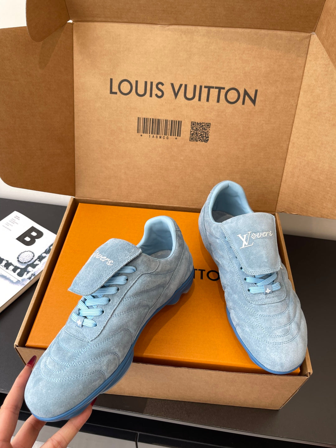 Light blue lace-up sneakers with Louis Vuitton logo, pair shown in open box