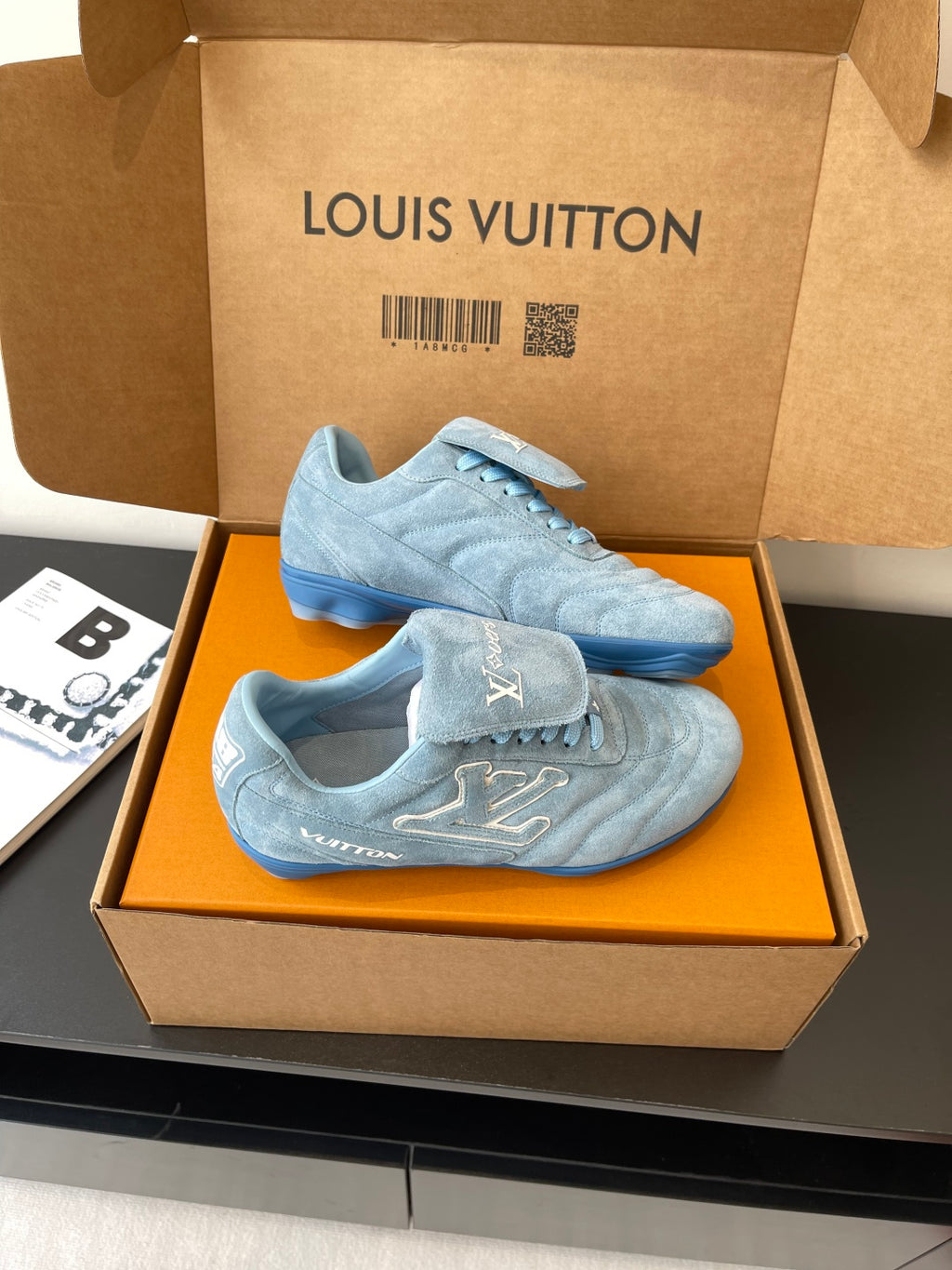 Light blue lace-up sneakers with Louis Vuitton logo, pair displayed in open box