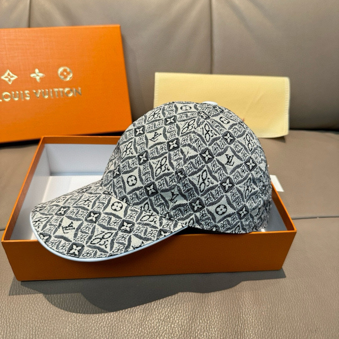 Monogram-pattern baseball cap in dark gray/black, curved brim, side view on box.