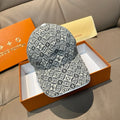 Monogram-pattern baseball cap in dark gray/black with curved brim, displayed on box.