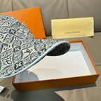 Monogram-pattern baseball cap brim and side panel in dark gray/black, close view.