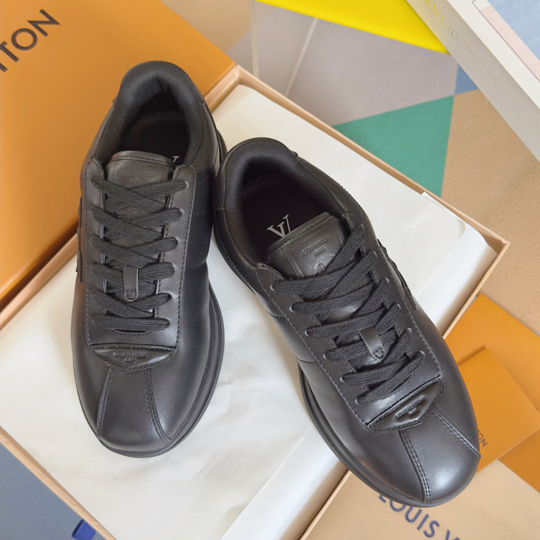 Black leather lace-up sneakers pair, front toe and lace detail visible