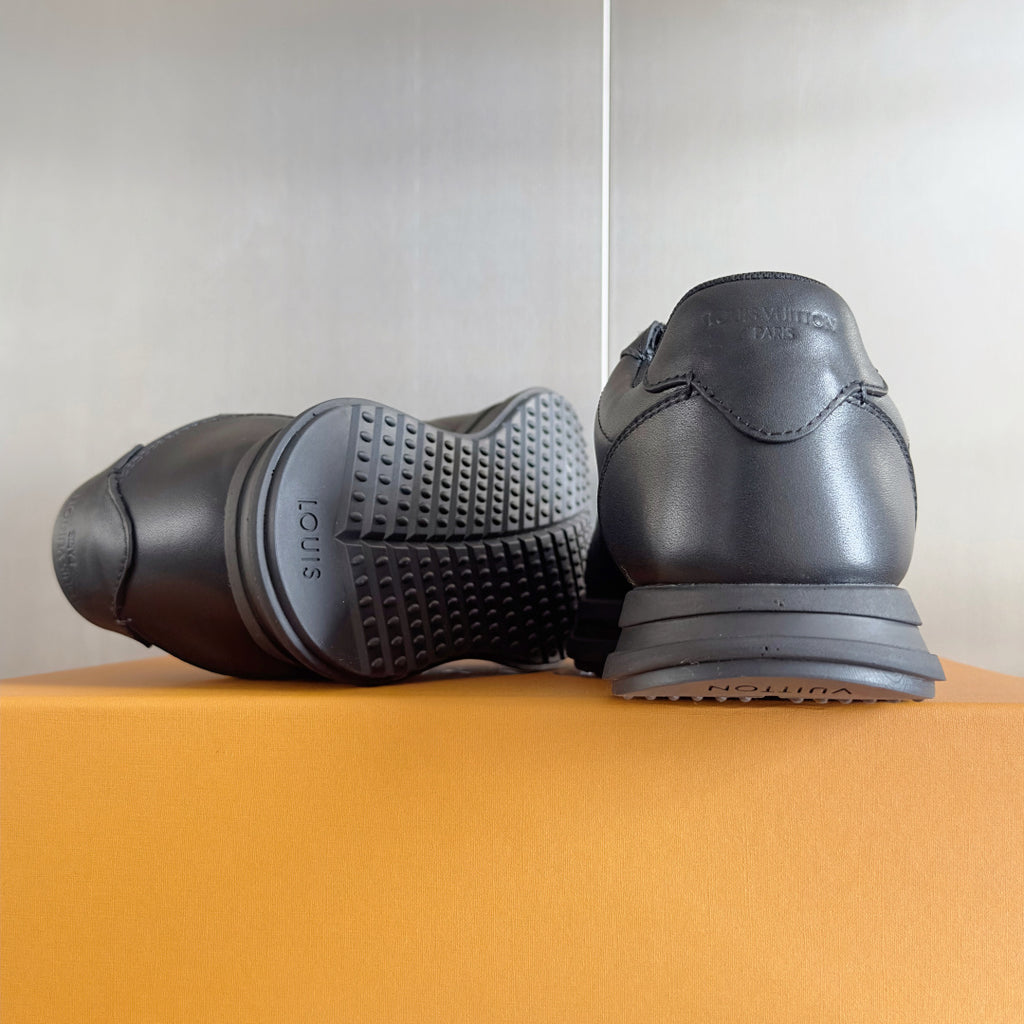 Black leather sneakers shown from heel and outsole sides with tread detail