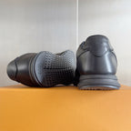Black leather sneakers shown from heel and outsole sides with tread detail