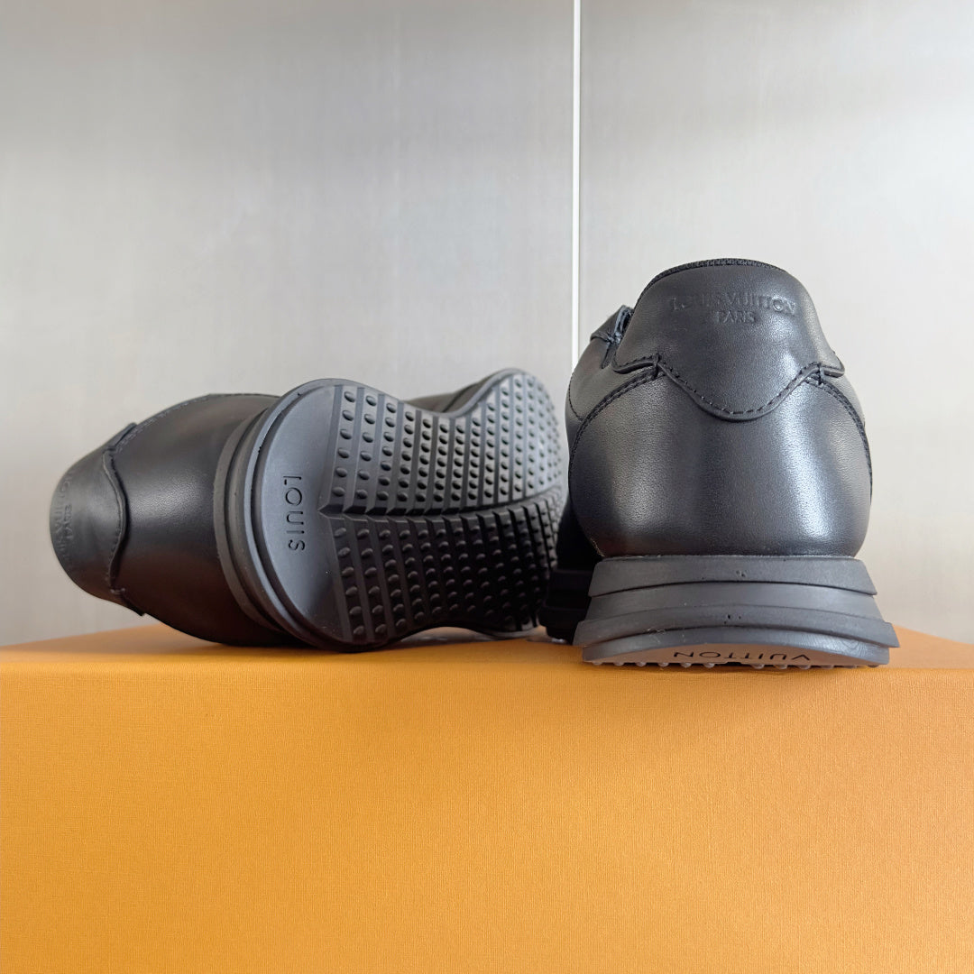 Black leather sneakers shown from heel and outsole sides with tread detail