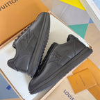 Black leather sneakers in a box, side profile view with embossed emblem