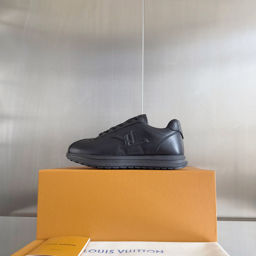 Black leather low-top sneaker on an orange box, lace-up style with side logo