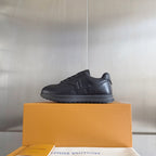 Black leather low-top sneaker on an orange box, lace-up style with side logo