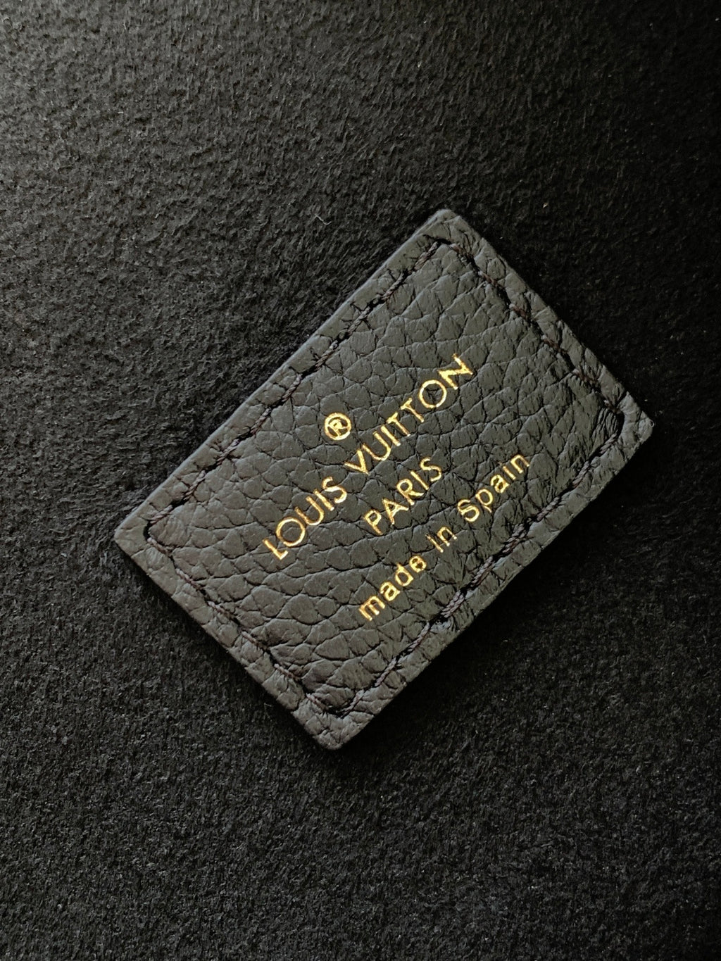 Louis Vuitton Paris embossed card tag on dark textured leather