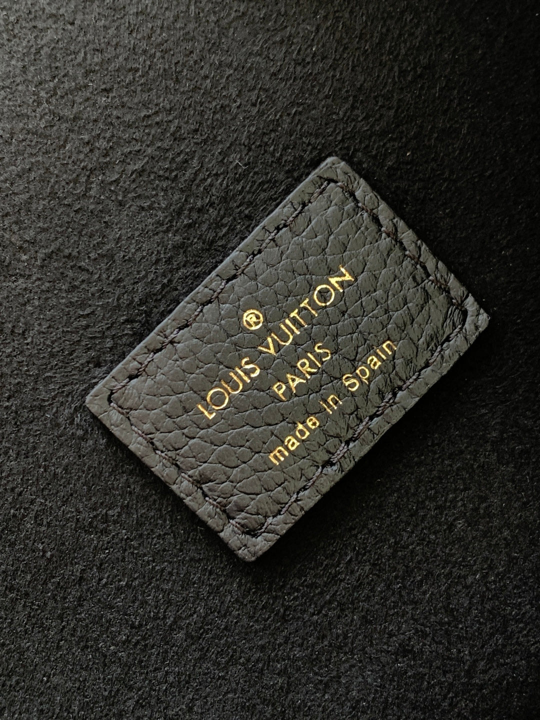 Louis Vuitton Paris embossed card tag on dark textured leather