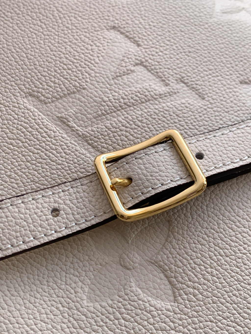 Louis Vuitton leather strap with gold-tone buckle on light beige pebble-grain material