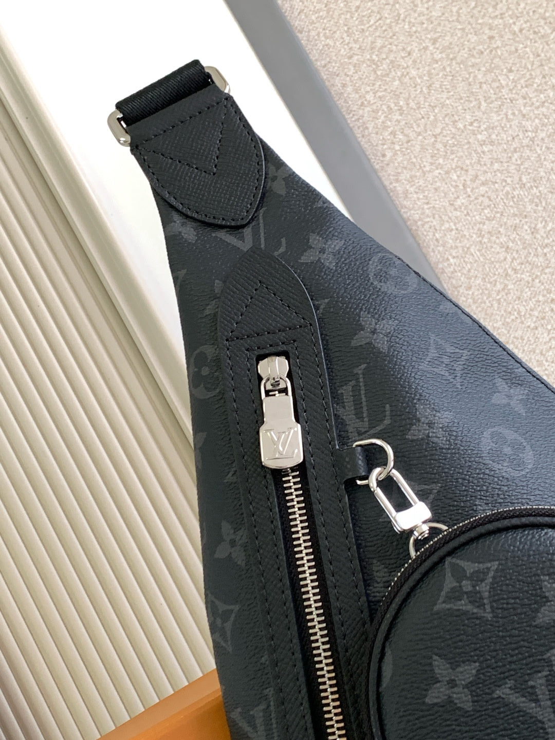 Louis Vuitton monogram crossbody bag with top zipper, keyring clip, and pull tab