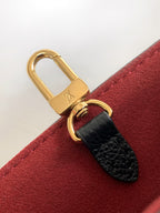 Louis Vuitton bag clasp close-up with gold lock and black leather strap on red lining
