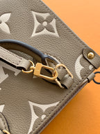 Close-up of Louis Vuitton taupe monogram bag with gold D-ring strap attachment