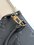 Black leather bag front flap with gold-tone clasp and embossed monogram