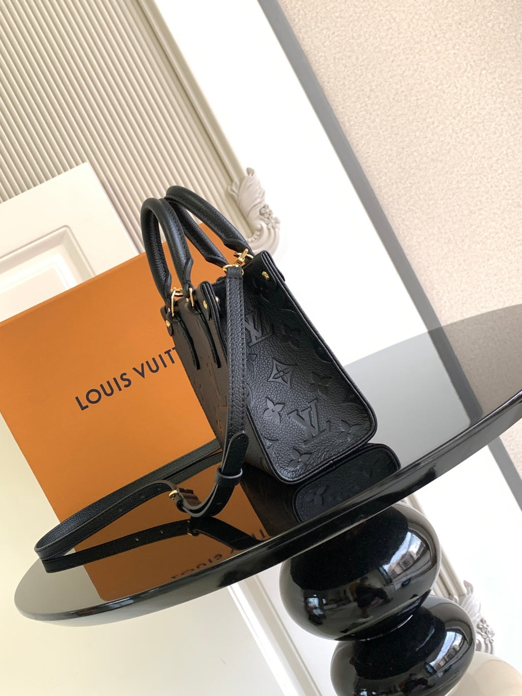 Black embossed leather tote bag with top handles and adjustable shoulder strap