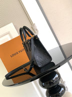 Black embossed leather tote bag with top handles and adjustable shoulder strap