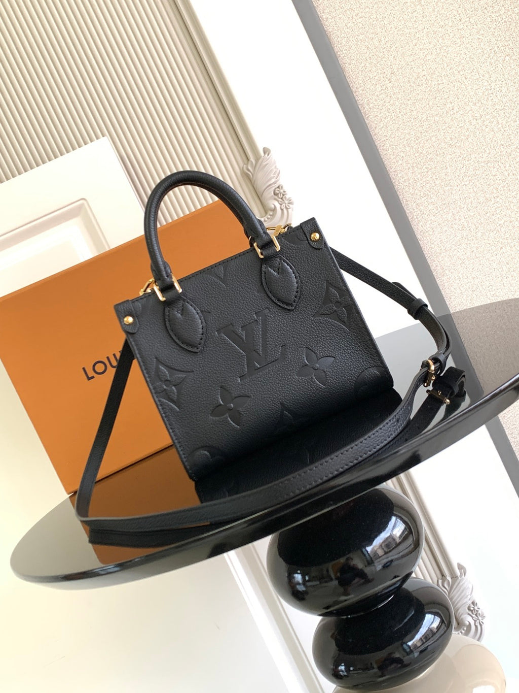 Black embossed leather tote bag with top handles and long strap