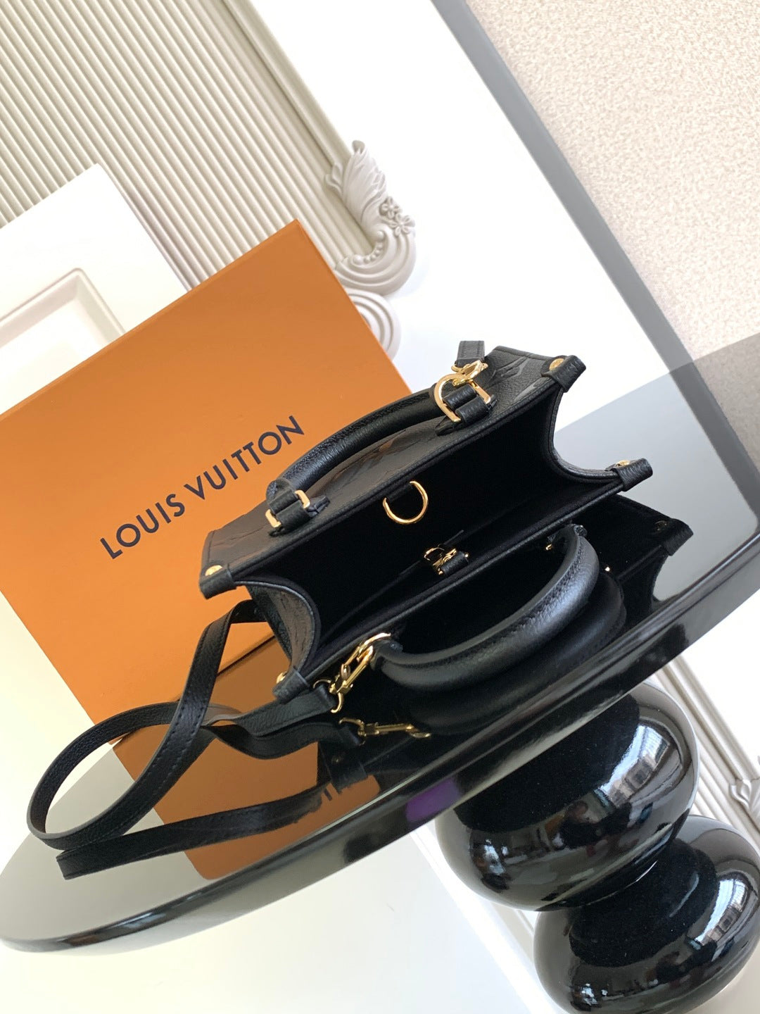 Black embossed leather top-handle bag with detachable strap and gold hardware