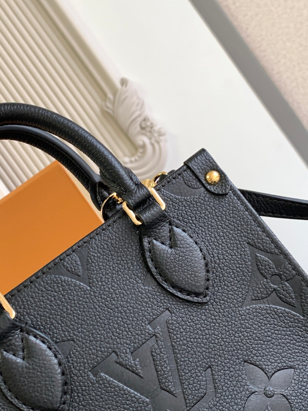 Black embossed leather tote bag front with stitched pocket and gold clasp
