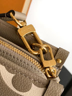 Gray monogram handbag hardware close-up with gold clasp and zipper ring