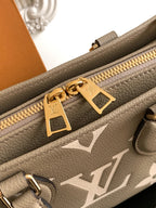 Gray monogram handbag close-up: gold zipper pull and logo plate on leather