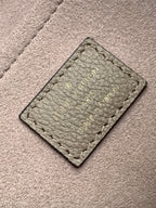 Embossed leather tag on gray monogram handbag