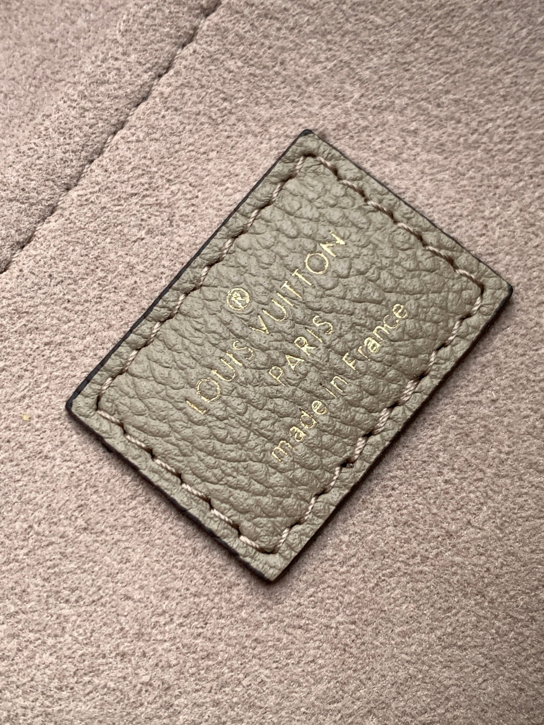 Embossed leather tag on gray monogram handbag