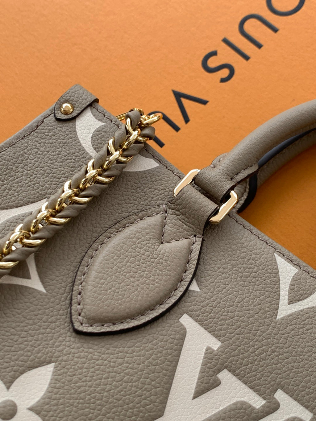 Gray monogram handbag detail with front logo hardware and braided chain