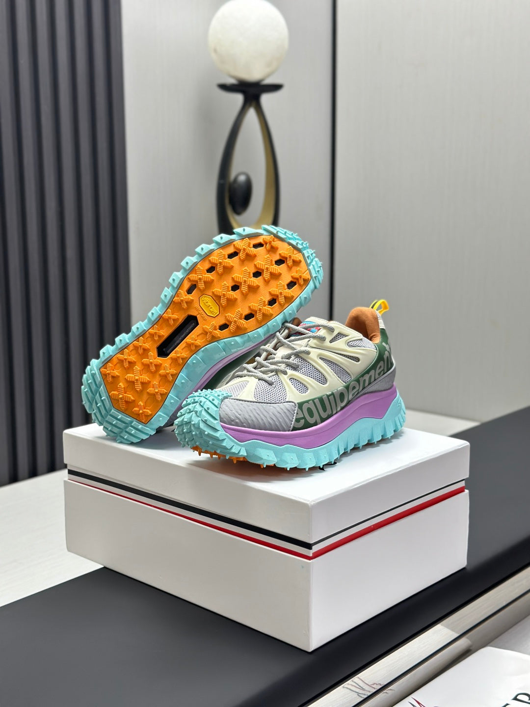 Grey lace-up sneakers with mint outsole tread and orange-speckled underside.