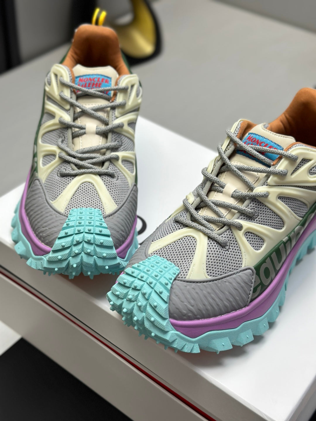 Grey sneakers with turquoise studded cuffs and purple midsole detail.