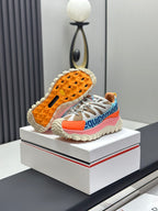 Moncler trail sneaker with visible tread sole, white laces and orange outsole, colorful panels