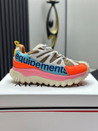 Moncler trail sneaker side view, white laces with orange toe panel, pink midsole, blue accent