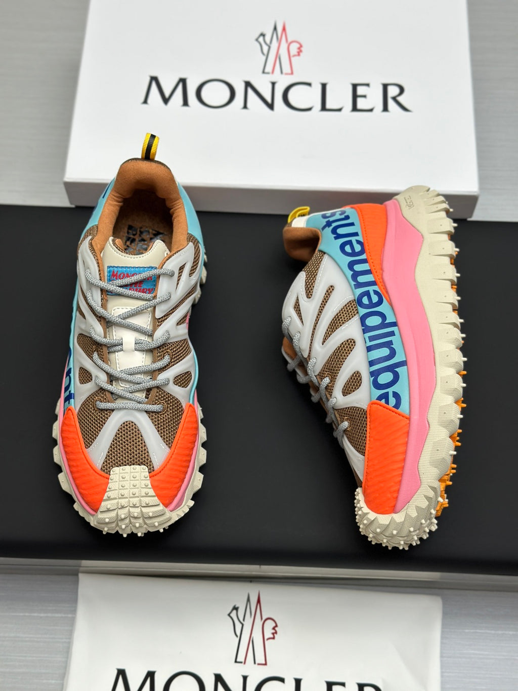 Moncler trail sneaker pair, white and tan uppers with orange side panels and pink sole edge