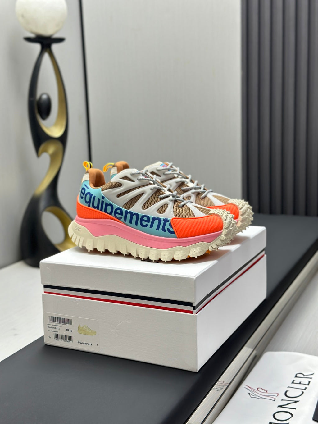 Moncler trail sneakers on a box, white laces with orange and pink trim, rugged sole