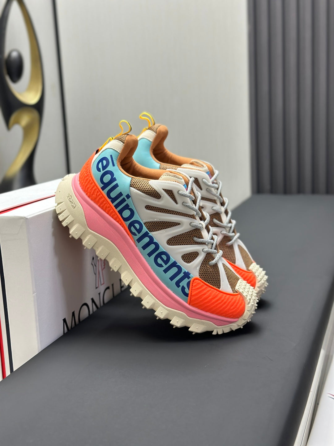 Moncler trail sneaker with white laces, orange inset and pink sole edge, side logo detail